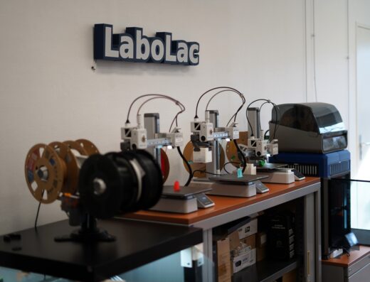 Imprimantes 3D alignées sur un plan de travail sous le logo LaboLac dans un atelier professionnel.
