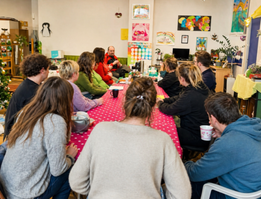 Un groupe de personnes assises autour d'une table rose à pois lors d'une réunion collaborative.